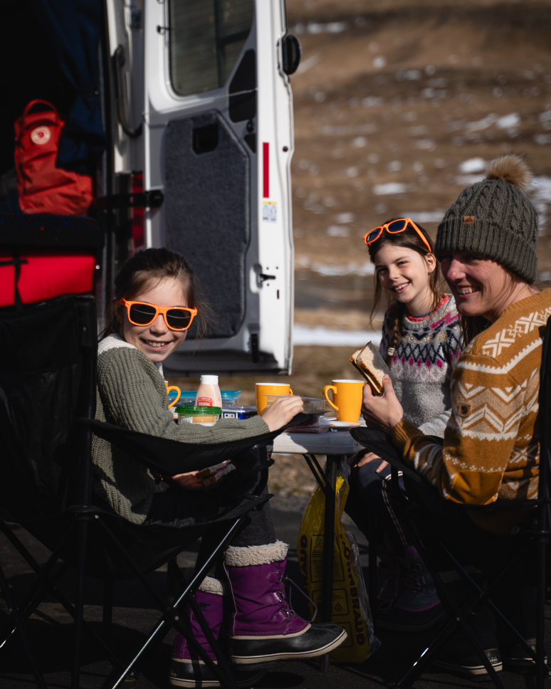 What to wear in Iceland in winter: the best clothing for Iceland from October to April family caming in iceland with hot chocolate milk next to the camper
