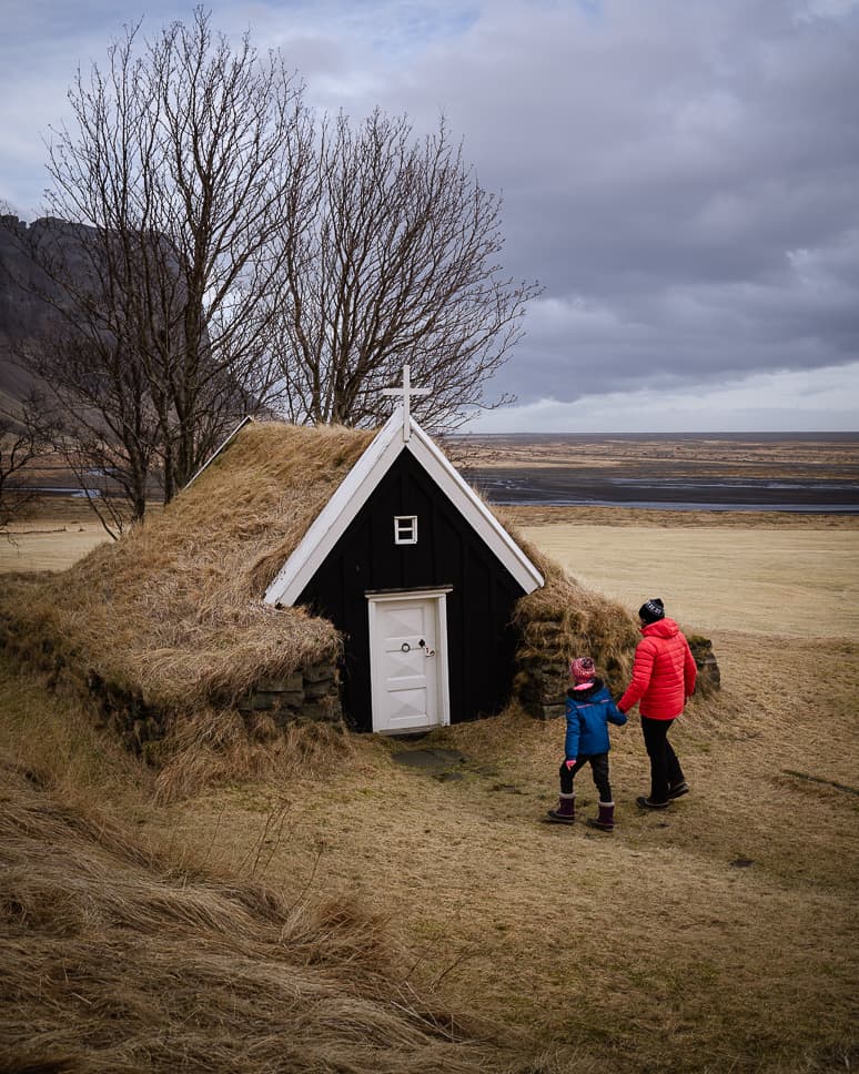 Father and kid walking to a chapel in Nupsstadur in Iceland