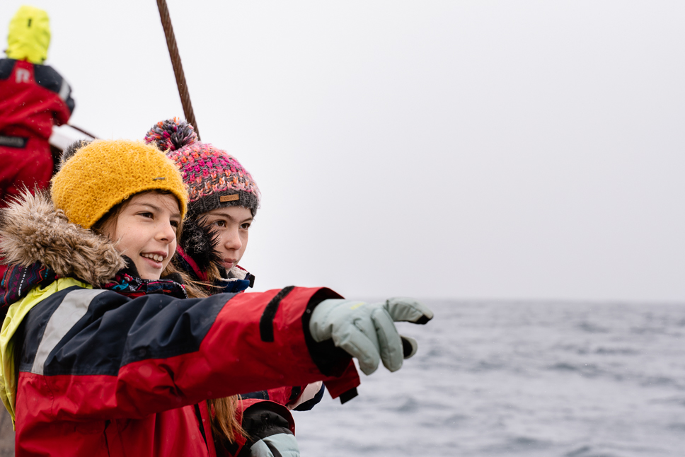 15 best and most impressive things to do in Iceland two kids looking for whales on a boat in iceland
