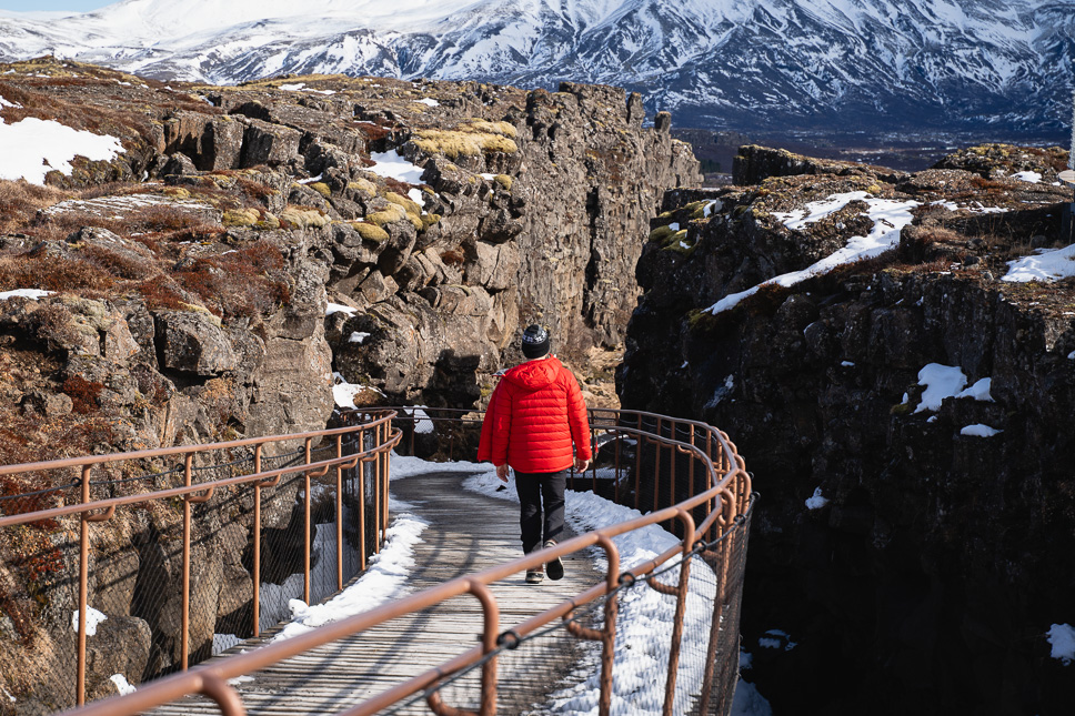 20+ Best things to do in Iceland: Our Ultimate Iceland Bucket List Man walks between the North American and Eurasian tectonic plates in Thingvellir National Park in Iceland