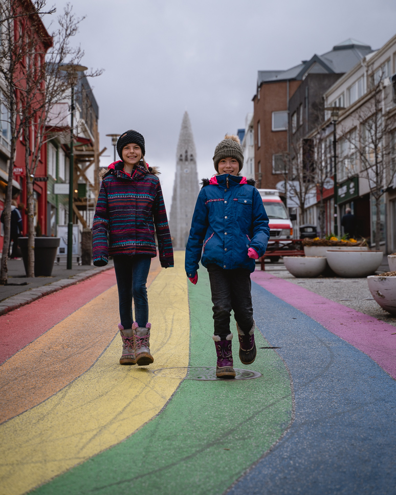 The best things to do in Reykjavik, Iceland + TIPS two kids walking and smiling in rainbow street in reykjavik in iceland